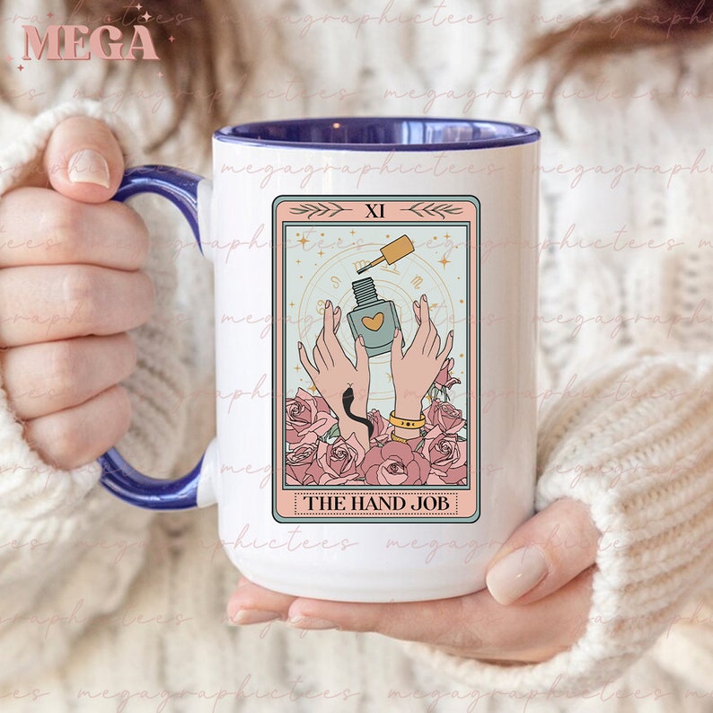 May include: White ceramic mug with a blue handle. The mug features a pink and white tarot card design with a hand holding a bottle of nail polish. The card reads "XI THE HAND JOB".