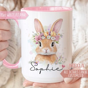 May include: White ceramic mug with a pink interior and handle. The mug features a watercolour illustration of a bunny wearing a floral crown. The name "Sophie" is written in script. The mug is labeled "15oz WHITE/LT.PINK".