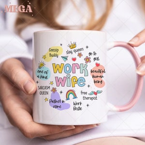 K&ouml;nnte beinhalten: Eine wei&szlig;e Keramiktasse mit einem rosafarbenen Henkel. Die Tasse hat ein farbenfrohes Design mit dem Text "Work Wife" und S&auml;tzen wie "Gossip Buddy", "Slay Queen", "Go To Girl", "One Of A Kind", "Sarcasm Queen", "Beautiful Human Being", "Free Therapist", "Partner In Crime" und "Work Bestie".