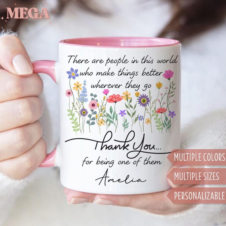 May include: White ceramic mug with a pink interior and handle, featuring a floral design and the text "There are people in this world who make things better wherever they go. Thank You... for being one of them Amelia." The mug is personalized.