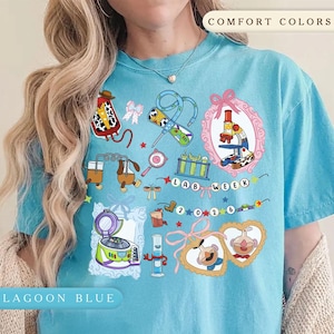 May include: Lagoon blue t-shirt with a colourful graphic design. The design includes lab-themed illustrations such as a microscope, test tubes, and a centrifuge. The text "LAB WEEK 2026" is also featured.