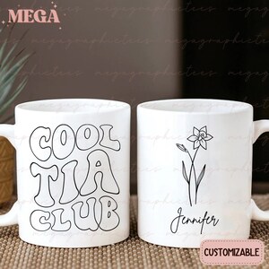 May include: Two white ceramic mugs with black designs. The mug on the left has the text "COOL TIA CLUB" in a retro font. The mug on the right has a simple line drawing of a daffodil and the name "Jennifer" written below it. The text "CUSTOMIZABLE" is printed in white on a black background below the mugs.