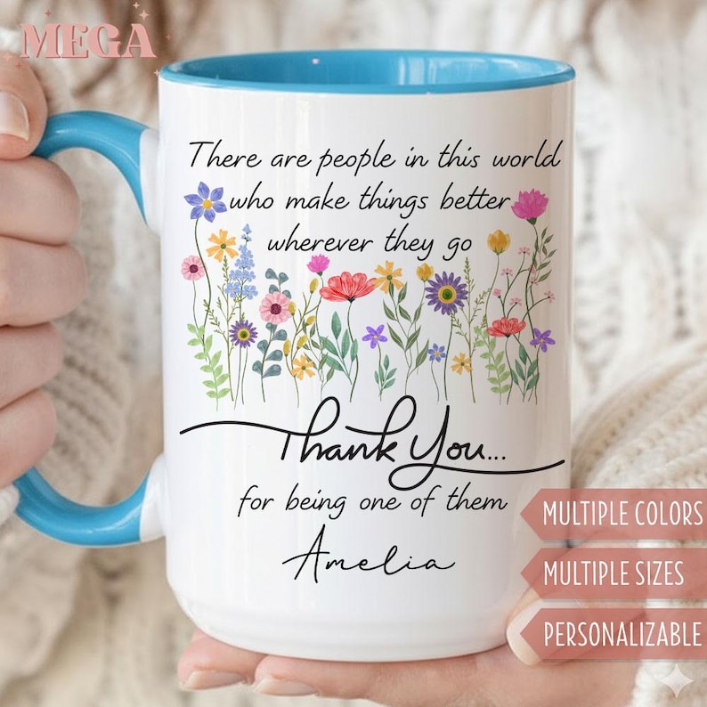 May include: White ceramic mug with a blue interior and handle. The mug features a floral design with the text "There are people in this world who make things better wherever they go. Thank You... for being one of them Amelia."