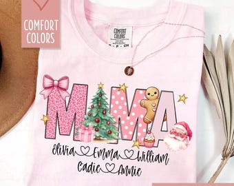 Könnte beinhalten: Hellrosa T-Shirt mit dem Wort "MAMA" in einem festlichen Design. Das "M" hat einen rosa Leopardenmuster, das "A" zeigt einen Weihnachtsbaum und das andere "M" hat rosa Tupfen. Enthält Namen und Urlaubs-Grafiken.