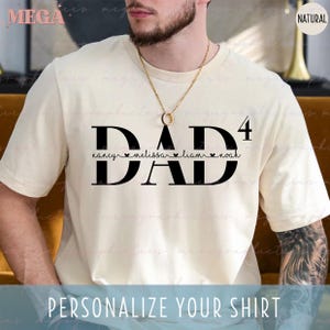 May include: A white t-shirt with the word "DAD" in black letters and the number "4" above it. The text "nancy melissa liam noah" is written below the word "DAD" with a heart symbol between each name.