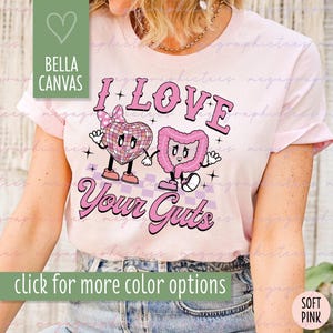 May include: A pink t-shirt with a graphic design of a heart and a cartoon intestine. The text "I Love Your Guts" is printed on the shirt.