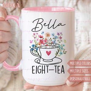 Könnte beinhalten: Eine weiße Keramiktasse mit rosafarbenem Rand, verziert mit einem Blumendesign mit einer Teetasse und Untertasse in der Mitte. Der Text "Bella Eight-Tea" ist auf die Tasse gedruckt. Die Tasse ist personalisierbar und in verschiedenen Farben und Größen erhältlich.