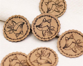 May include: A set of six brown leather patches featuring a black outline of a fox face. Each patch has a decorative border of leaves and vines.