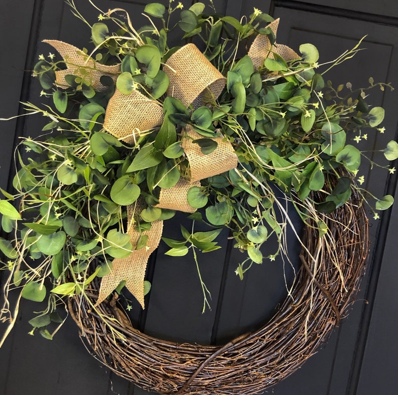May include: A brown twig wreath with a burlap bow and green eucalyptus leaves.