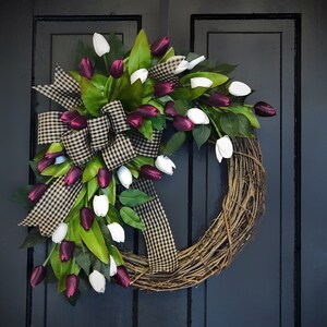 May include: A grapevine wreath decorated with white and burgundy artificial tulips and a black and white checkered ribbon.
