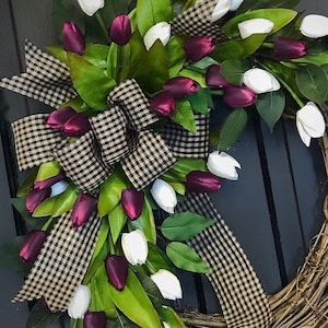 May include: A grapevine wreath with a black and white checkered ribbon and a cascade of white and burgundy tulips.