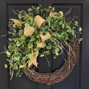 May include: A brown twig wreath with a burlap bow and green eucalyptus leaves.