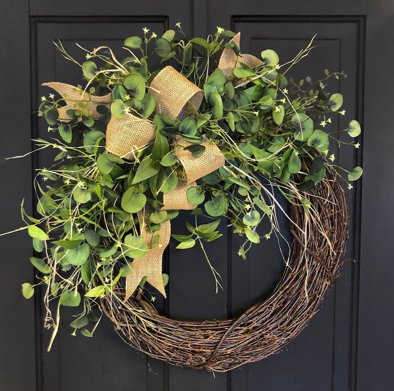 May include: A brown twig wreath with a burlap bow and green eucalyptus leaves.
