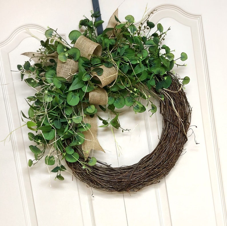 May include: A brown twig wreath with a burlap bow and green eucalyptus leaves.