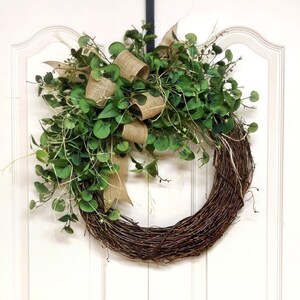 May include: A brown twig wreath with a burlap bow and green eucalyptus leaves.
