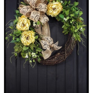 Pode incluir: Uma coroa de videira com um la&ccedil;o de juta e flores amarelas. O la&ccedil;o tem um padr&atilde;o de espiral preto e branco.