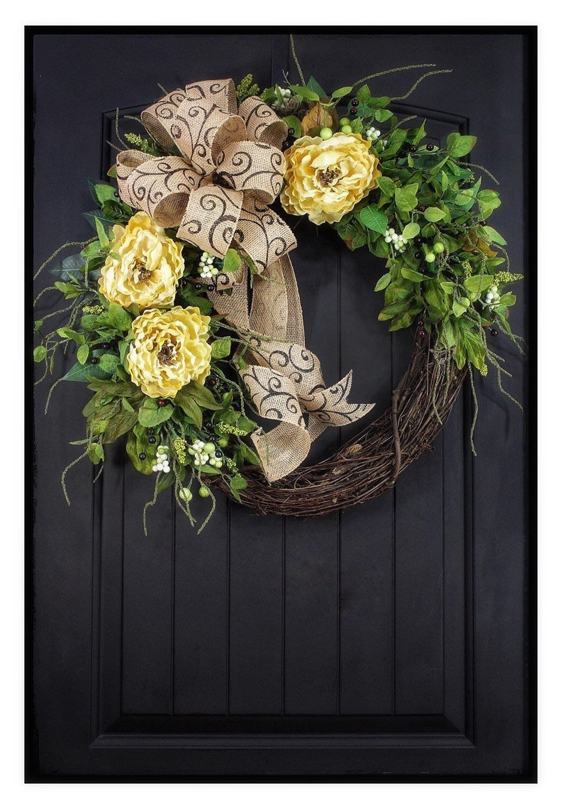 Pode incluir: Uma coroa de videira com um la&ccedil;o de juta e flores amarelas. O la&ccedil;o tem um padr&atilde;o de espiral preto e branco.