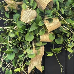May include: A green wreath with a burlap bow. The wreath is made of twigs and has a rustic look.