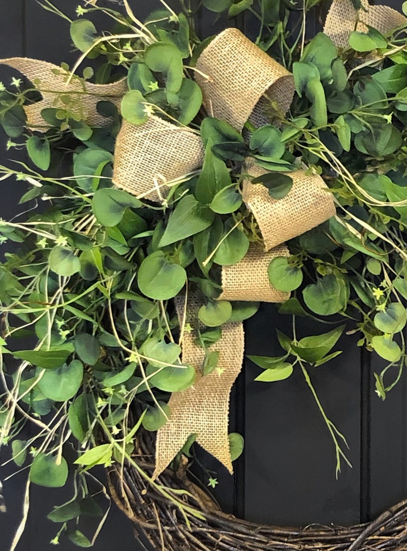 May include: A green wreath with a burlap bow. The wreath is made of twigs and has a rustic look.