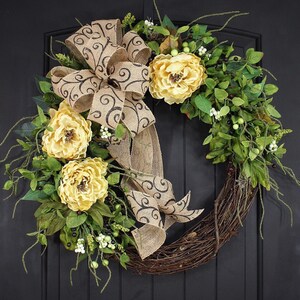 Pode incluir: Uma coroa de videira com um la&ccedil;o de juta e flores amarelas. O la&ccedil;o tem um padr&atilde;o de espiral preto.