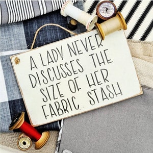 A lady never discusses the size of her fabric stash • Sewer gift • Sewing room • Sewing • Sewing quote • Fabric addict • Hanging sign