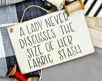A lady never discusses the size of her fabric stash • Sewer gift • Sewing room • Sewing • Sewing quote • Fabric addict • Hanging sign