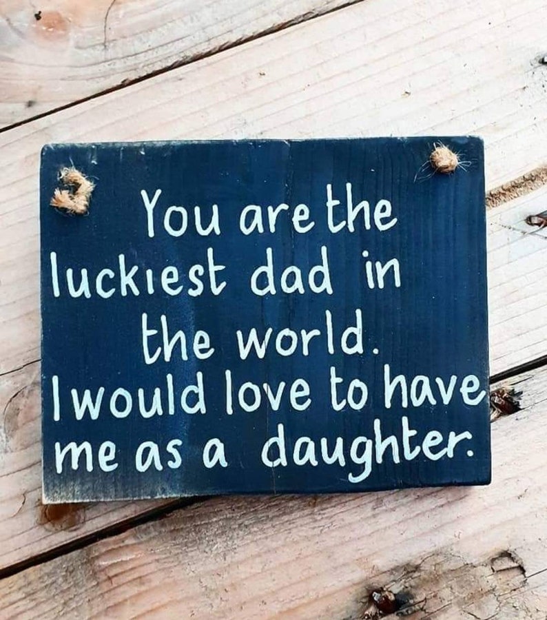 May include: A black wooden sign with white text that reads "You are the luckiest dad in the world. I would love to have me as a daughter."