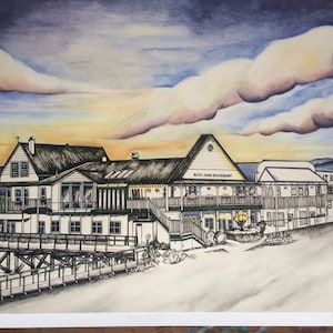 May include: Watercolor painting of a restaurant and pier at sunset. The building is white with black trim and the text "Ruth Ann Restaurant" is visible. The sky is a mix of blue, orange, and purple.