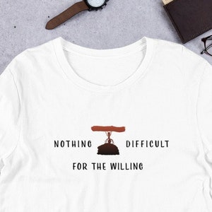 Może przedstawiać: Biały t-shirt z krótkim rękawem z grafiką przedstawiającą mrówkę niosącą dużą kłodę nad głową. Pod grafiką znajduje się napis "NOTHING DIFFICULT FOR THE WILLING" wykonany prostą czarną czcionką, umieszczony centralnie na klatce piersiowej.