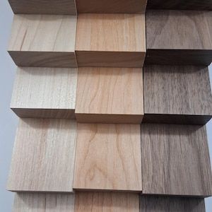 May include: A close-up of a wooden block arrangement featuring various wood types and grains. The blocks are stacked in a staggered pattern, showcasing the natural colors and textures of the wood. The arrangement highlights the different shades of brown and tan.