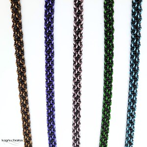 May include: Five strands of chainmaille, each with a different coloured wire. The chains are made with black wire and a second coloured wire. The colours are gold, purple, pink, green, and blue.