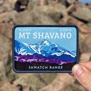 May include: A rectangular patch featuring a mountain landscape with the text "MT SHAVANO" and "SAWATCH RANGE". The patch also includes the elevation in feet and meters. The background shows a rocky mountain peak with people.
