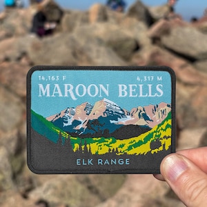 May include: A rectangular patch featuring a mountain landscape with the text "MAROON BELLS" and "ELK RANGE". The patch includes the elevation in feet and meters. The design incorporates shades of blue, green, yellow, and pink, with a black border.