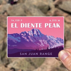 May include: A pink and purple illustrated sticker of El Diente Peak in the San Juan Range. The sticker shows a mountain range with snow-capped peaks and a pink sky. The text on the sticker reads "14,159 ft. El Diente Peak 4,315 m. San Juan Range".