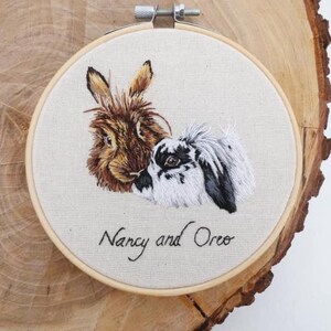 May include: Embroidered portrait of two rabbits, one brown and one black and white, with the names "Nancy and Oreo" stitched below.