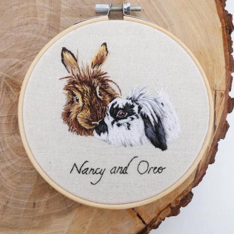 May include: Embroidered portrait of two rabbits, one brown and one black and white, with the names "Nancy and Oreo" stitched below.