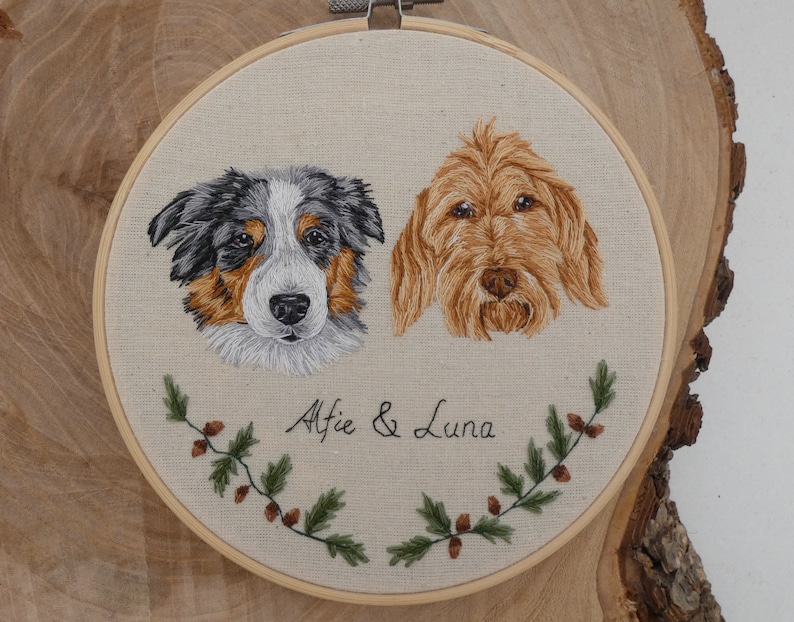 May include: Embroidered portrait of two dogs, a blue merle Australian Shepherd and a golden doodle, with their names "Alfie & Luna" stitched below. The portraits are surrounded by green leafy vines with brown berries.