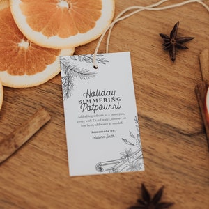 May include: A wooden cutting board with orange slices, cinnamon sticks, star anise, and a tag that reads "Holiday Simmering Potpourri." The tag includes instructions and is decorated with botanical illustrations.
