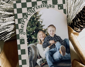 May include: Christmas card with a photo of two children, framed by a green and white checkered border. The words "Merry Christmas" are arched above the photo. The card is decorated with pine needles and a pine cone.