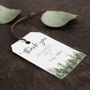 May include: White thank you tag with a watercolor forest design. The tag says "Thank you for celebrating with us" and "Carly & Nathan".