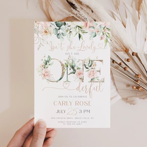 Puede incluir: Una invitación de primer cumpleaños con temática floral con un "uno" de purpurina dorada rodeado de flores rosas y blancas. El texto dice "¿No es hermosa?" y "derful" con la fecha y hora de la fiesta: 25 de julio, 3 PM.