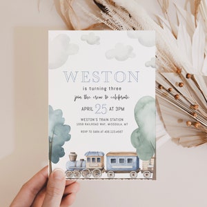 May include: A blue and white train invitation with clouds and trees. The invitation says "Weston is turning three, join the crew to celebrate, April 25 at 3pm, Weston's Train Station, 1058 Railroad Way, Missoula, MT, RSVP to Sara at 406.123.4567".