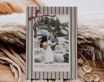 Könnte beinhalten: Eine Weihnachtskarte mit einem Foto eines Paares, das sich vor einer Bergkulisse umarmt. Die Karte hat einen gestreiften Rand in Grau und Rot mit einem roten Schleifendesign. Der Text "MERRY CHRISTMAS" ist auf der Karte zu sehen.