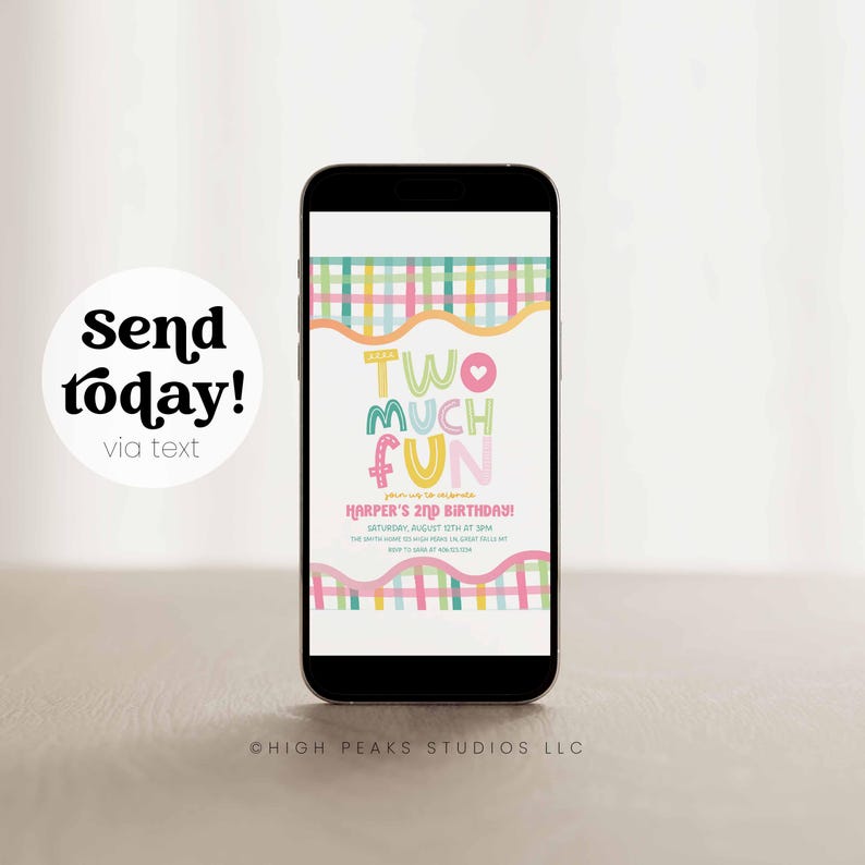 May include: A black smartphone displays a colorful birthday invitation with the text "TWO MUCH FUN." The invitation includes details for Harper's 2nd birthday, with a playful design featuring pastel colors and a whimsical font. The phone is on a light surface.
