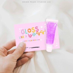 May include: Pink Valentine's Day card with the text "Gloss Like A Boss! Happy Valentine's Day!" and a small tube of purple lip gloss.