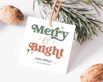 May include: White gift tag with green and orange text that reads "Merry & Bright" with small white stars. The text "Happy Holidays." and "THE ANDERSONS" are printed below the main text.