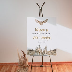 Puede incluir: Un cartel de boda blanco con una ilustraci&oacute;n de acuarela del castillo de Hogwarts y un b&uacute;ho dorado volando por encima. El texto dice "Bienvenido a la boda de Carly + Jonathan 11.23.20XX".