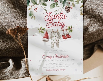 May include: A festive baby shower invitation with the words "Santa Baby" in elegant script. The design features a Santa hat, onesie, and boots hanging on a clothesline, with holly and snowflake accents. The invitation is for Carly Anderson.