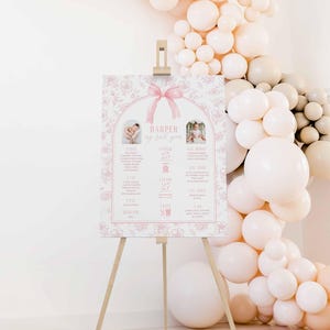 Puede incluir: Un póster floral rosa y blanco con una cinta rosa y un arco blanco. El póster dice "Harper my first year" e incluye detalles sobre el primer año de vida de un bebé, como el peso, la altura y las primeras palabras. Hay dos fotos del bebé a diferentes edades.