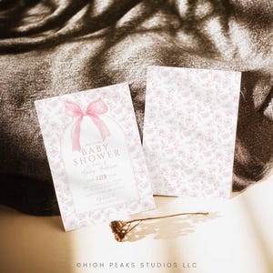 May include: A pink baby shower invitation with a pink bow and a floral pattern. The invitation reads "Join us to celebrate a Baby Shower in honor of Ashley Anderson, 12th 5pm".